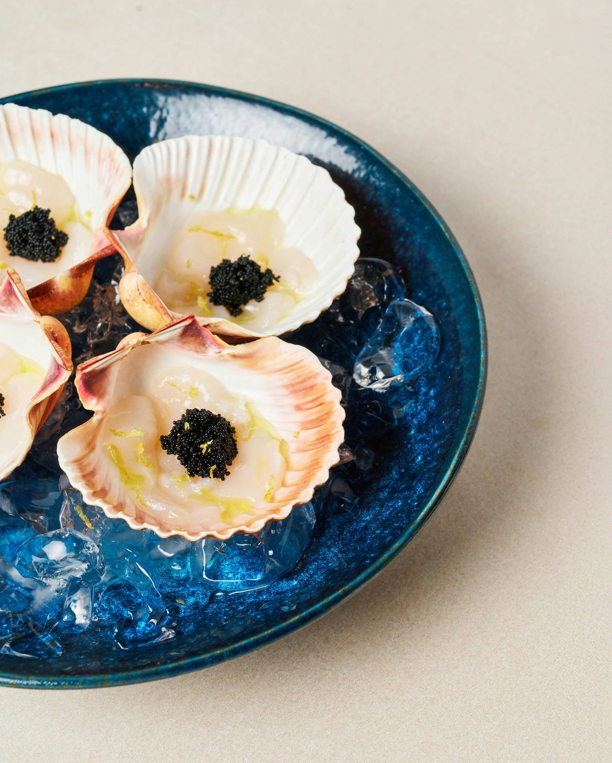 Raw scallops in the shell topped with caviar, served on ice